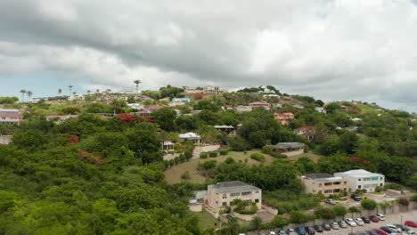 Aerial-revealing-view-houses-panorama-surrounded-by-tropical-nature-with-tourist-stand-by-pool