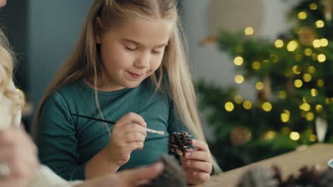 caucasian woman and daughter decorating cone with white paint.