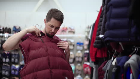 hombre intentando un chaleco de invierno en una tienda de ropa