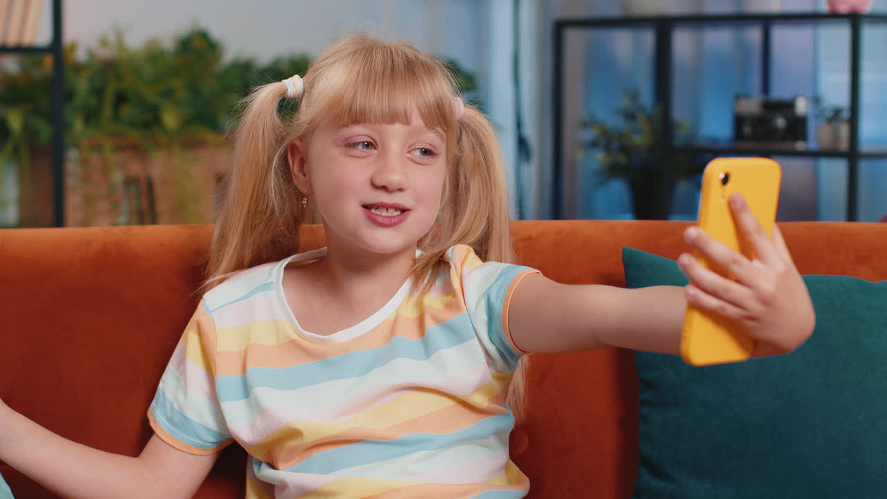 Child kid girl taking selfie on smartphone communicating video call home online with subscribers