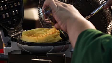 person preparing waffles using a waffle iron