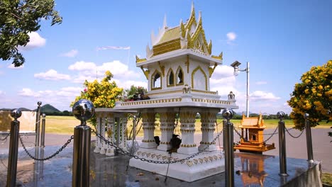 Ein-Lokales-Thailändisches-Geisterhaus-In-Der-Landschaft-Von-Lopburi,-Thailand,-Mit-Kleinen-Welpen,-Die-Sich-An-Einem-Heißen,-Sonnigen-Tag-Mit-Blauem-Himmel-Darunter-Verstecken