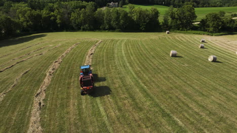 Tractor-harvesting-field-with-straw-harvester,-agriculture-summer,-aerial
