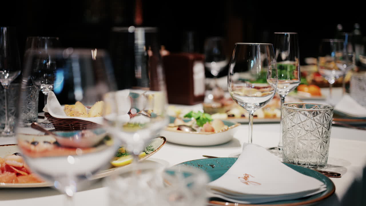 Refined restaurant table setting with crystal glasses, plates, and gourmet dishes in the background