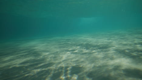 surfista remando para una ola en aguas cristalinas en la bahía de byron, australia, disparado desde debajo del agua en cámara lenta.