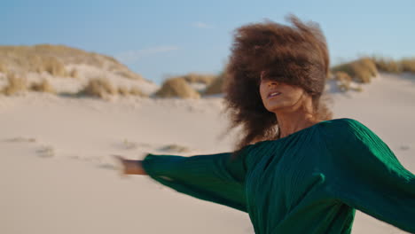 una chica expresiva realizando una danza contemporánea en el desierto de verano de arena de cerca.