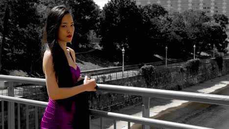 young woman in purple dress averting gaze and turn towards railing