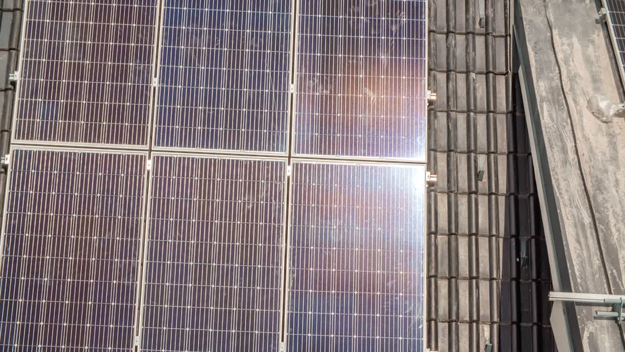 tiro inclinado hacia abajo que muestra una granja de paneles solares en el techo de una residencia durante un día soleado