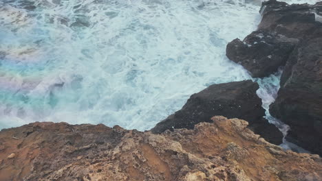 Una-Vista-De-Cerca-De-Las-Turbulentas-Olas-Del-Mar-Rompiendo-Contra-Escarpados-Acantilados,-Creando-Una-Demostración-Llena-De-Espuma-Del-Poder-De-La-Naturaleza