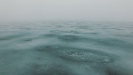 flight over frozen sea coast line with ice cracks in misty foggy cold winter day