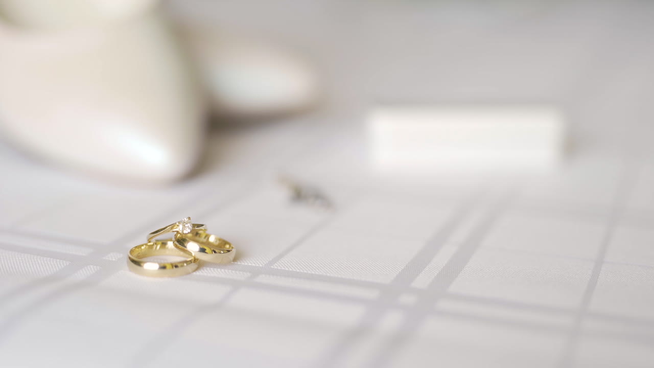 白い表面に置かれたダイヤモンド付きの輝くゴールドの結婚指輪