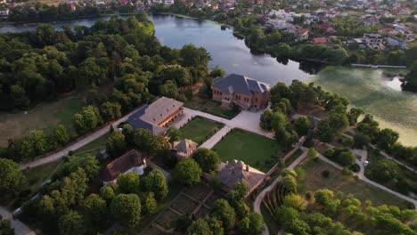 Mogoșoaia-palace-in-romania,-warm-sunset-hues,-with-greenery-and-water-,-aerial-view