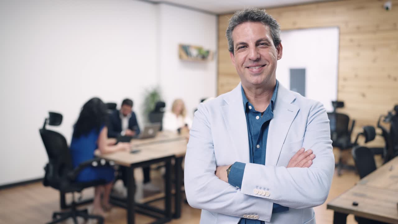 Empresario confiado sonriendo con los brazos cruzados en una oficina moderna