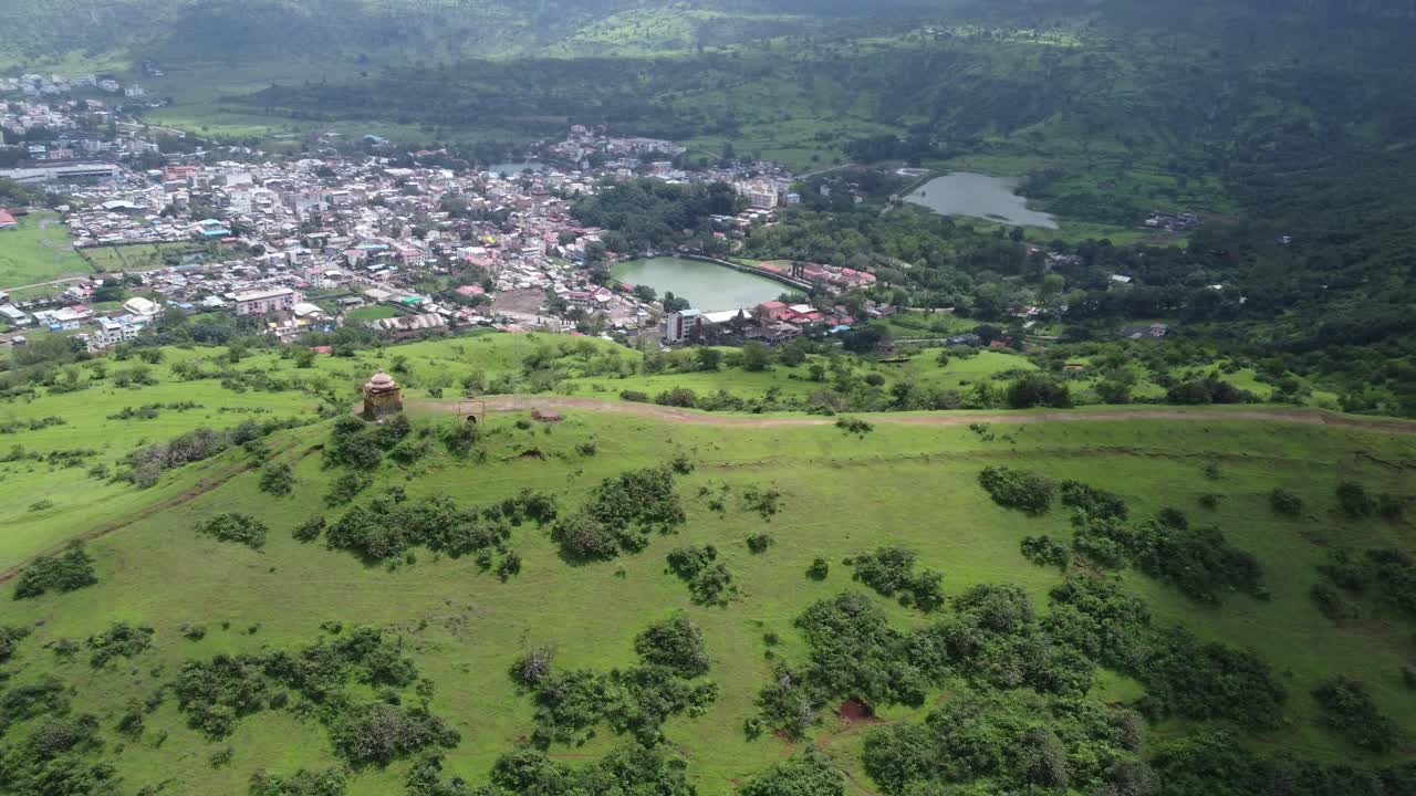 vista aérea del templo de lord shiva en el borde de la cima de la montaña con la vista de la ciudad de trimbkeshwar y la presa de ahilya en el fondo rodeada de exuberante vegetación, nashik, maharashtra, india
