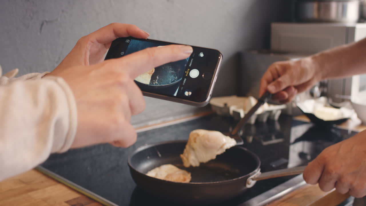 pareja tomando fotos usando el teléfono inteligente del desayuno fritando huevos para el estilo de vida de las redes sociales en casa en la cocina