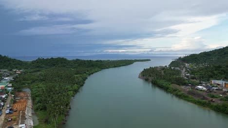 Epische,-Filmische-Luftaufnahme-Eines-Riesigen-Flusses-Zwischen-üppigen-Dschungeln-Und-Ländlichen-Gemeinden-Mit-Atemberaubender-Wolkenlandschaft