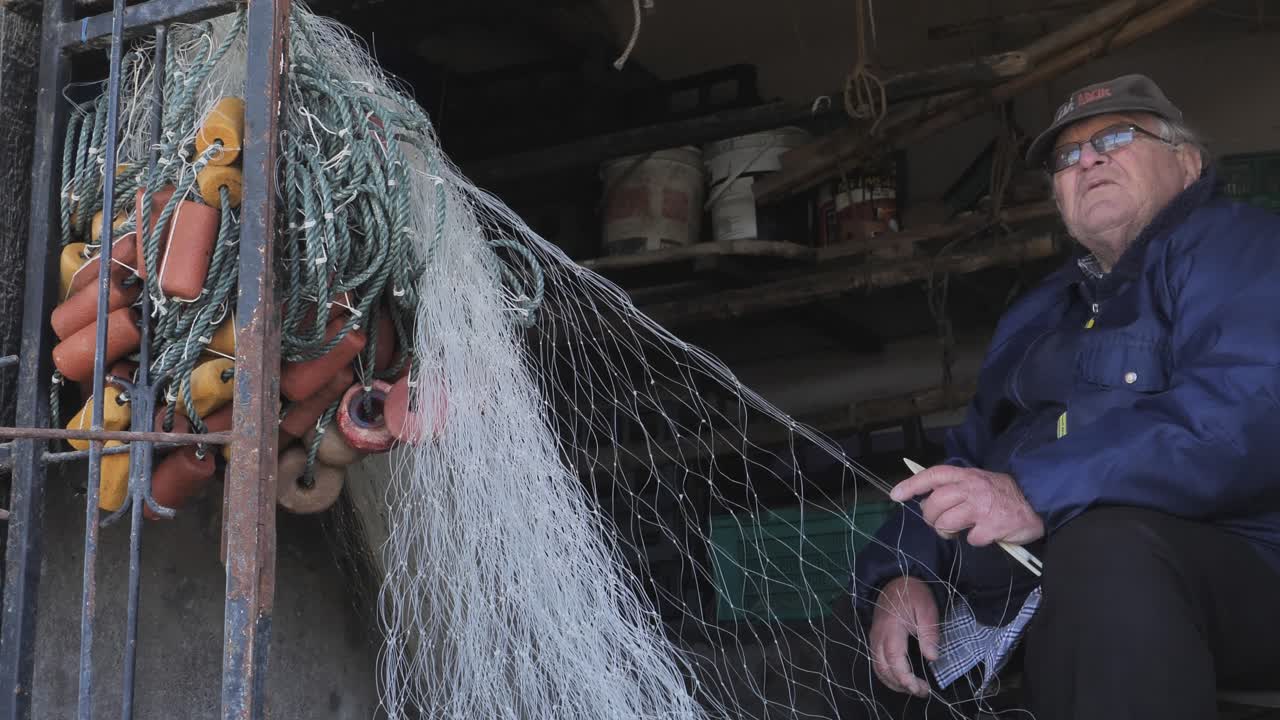 Elderly fisherman mends fishing nets in a rustic workshop in Bokkomlaan, Velddrif, South Africa