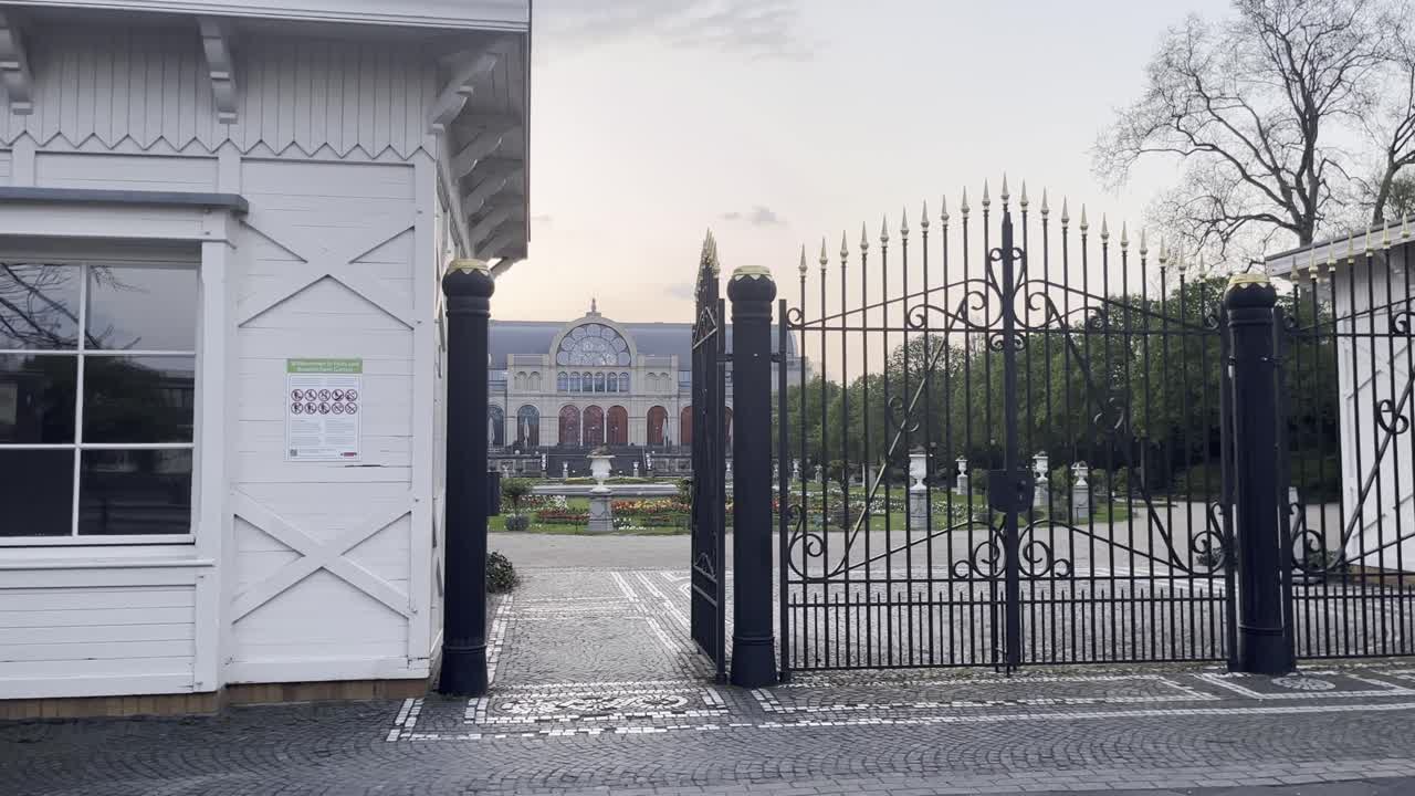 Entrance gate to a palace garden with small keeper's house and black gate with beautiful park, Cologne, Flora, Germany