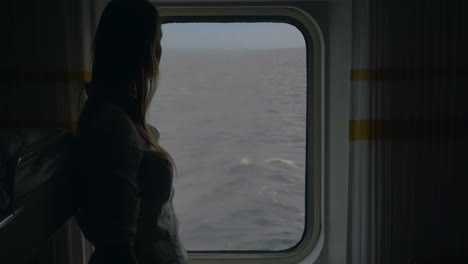 girl opening blind in cabin to look at the sea