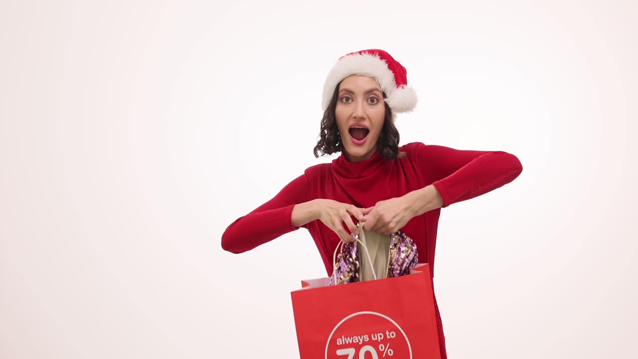 Woman in Santa Hat Excitedly Unboxes a Sequin Dress from a Shopping Bag