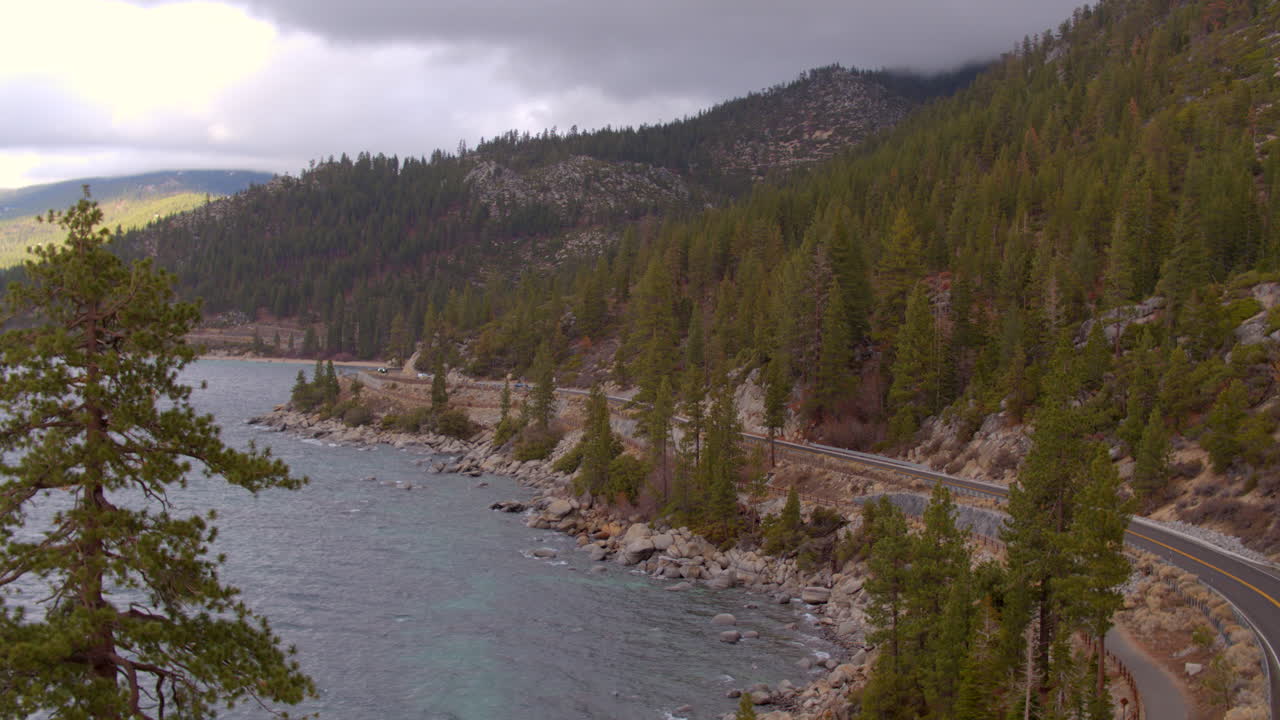 Veduta aerea di una strada che si snoda attorno al Lago Tahoe in Nevada in una bella giornata invernale con un abete di Douglas in primo piano.