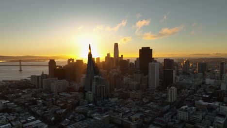 aerial view of sunrise behind the san francisco skyline. sunbeams cast over city