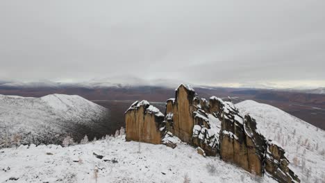 experimente un viaje aéreo impresionante sobre altas formaciones rocosas y montañas cargadas de nieve en un paisaje natural aislado durante los meses de invierno, mostrando la belleza de la naturaleza.