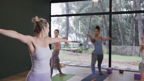 Focused-diverse-women-stretching-together-on-mats-in-yoga-class-with-female-coach,-slow-motion