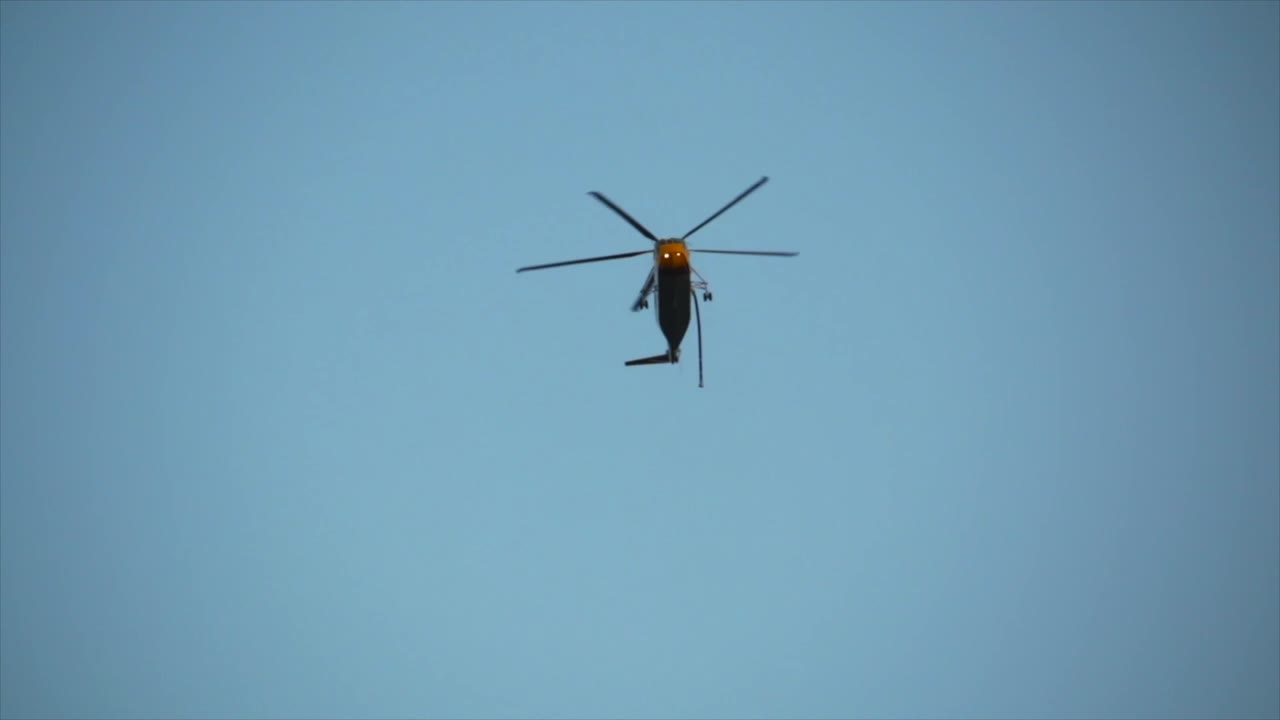 소방 헬리콥터는 근처의 격렬한 산불을 찾기 위해 물을 찾기 위해 머리 위로 낮게 날아갑니다.