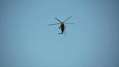 firefighting helicopter flies low overhead searching for water for nearby raging forest wildland fire