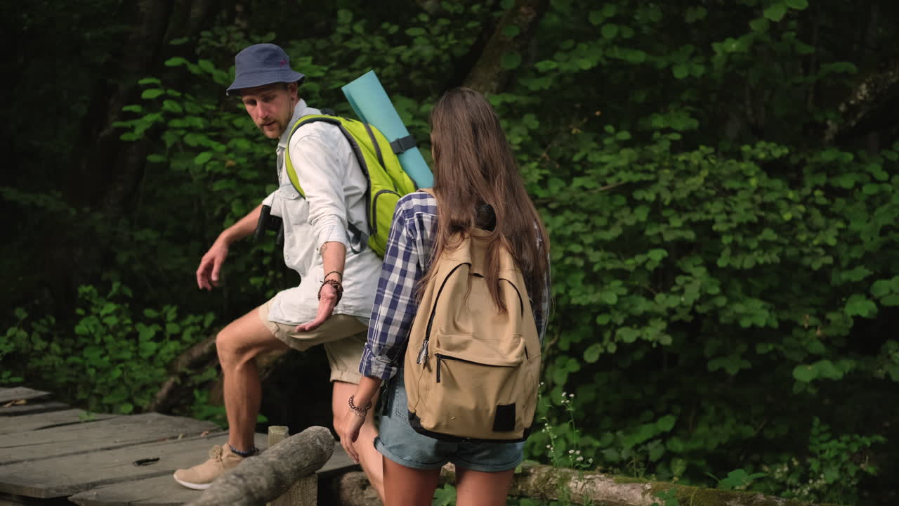 pareja de senderismo en un puente de madera en un bosque