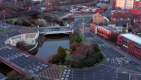 aerial early morning city street traffic commuting intersection lanes crossing curved river slow lowering tilt up