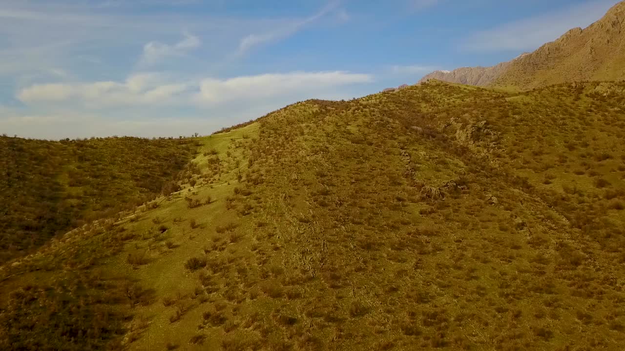 volar sobre la montaña de la colina seca en irán kermanshah tierras altas del noroeste con una amplia vista del paisaje natural en el clima de verano cielo azul claro nubes blancas