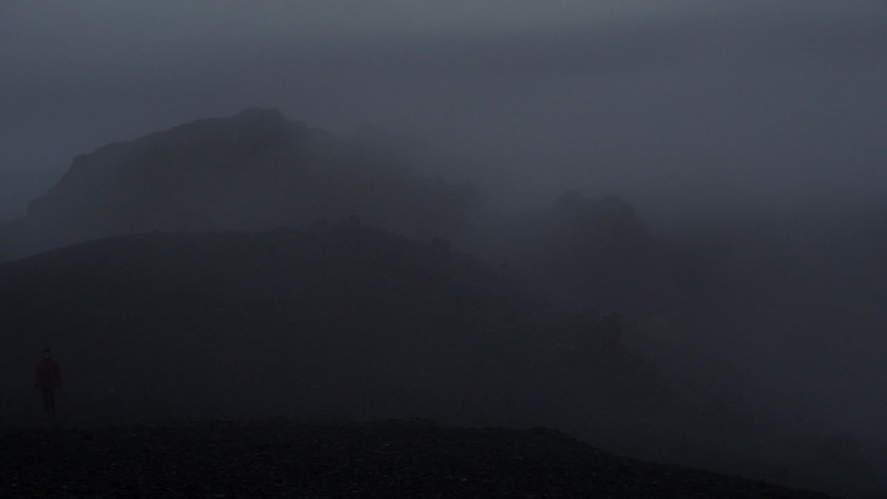 밤의 극적인 아이슬란드 풍경, 카메라 움직임, 카메라가 오른쪽에서 왼쪽으로 이동하여 카메라를 향해 걸어가는 사람을 보여줍니다.