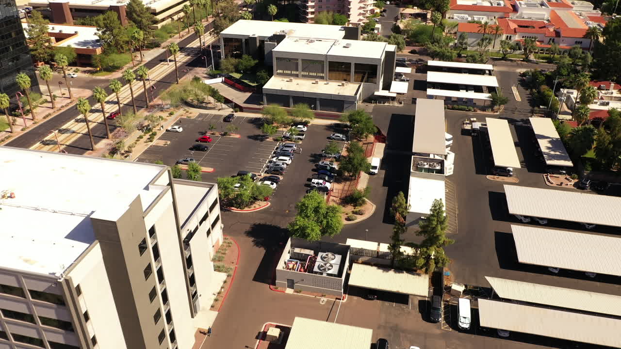 autos estacionados en un estacionamiento abierto con edificios de oficinas en un día soleado