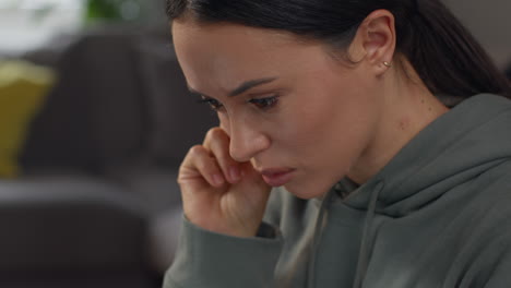 close up of anxious woman sitting indoors on sofa working from home using laptop worried about cost of living crisis 5