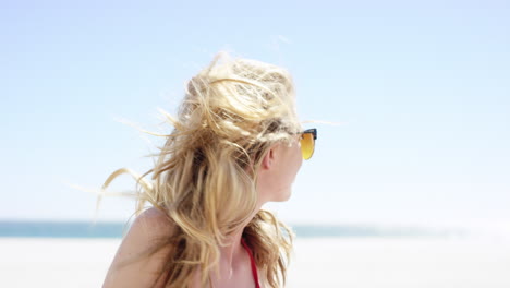 close up portrait of beautiful young teenage girl looking over shoulder with hair blowing in wind on tropical beach slow motion