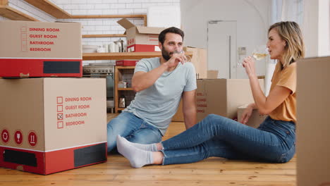 pareja celebrando mudarse a una nueva casa haciendo un brindis con vino