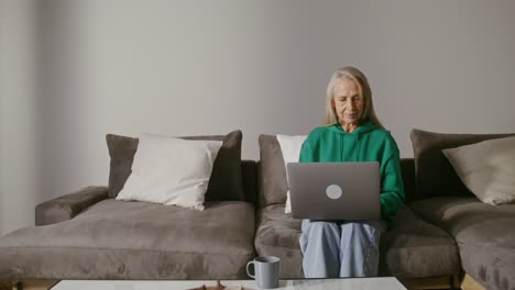 mujer mayor trabajando en una computadora portátil en casa