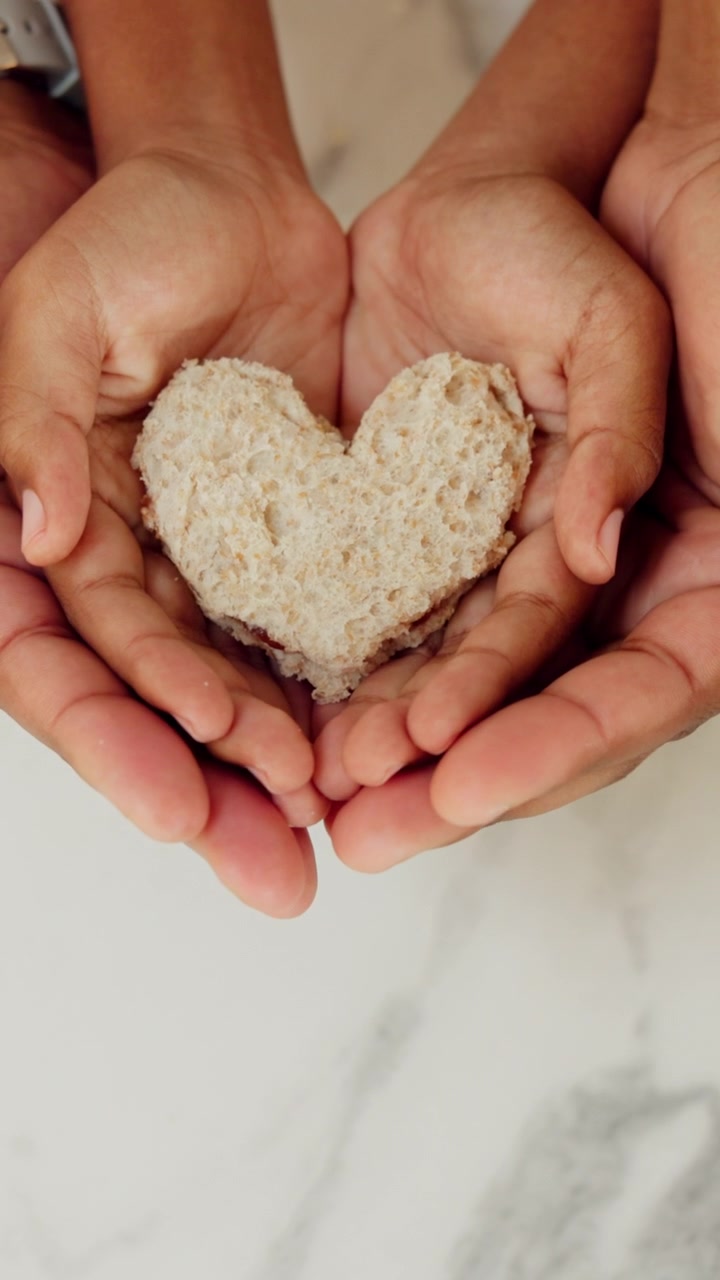 Padre e hijo sosteniendo juntos un pan con forma de corazón