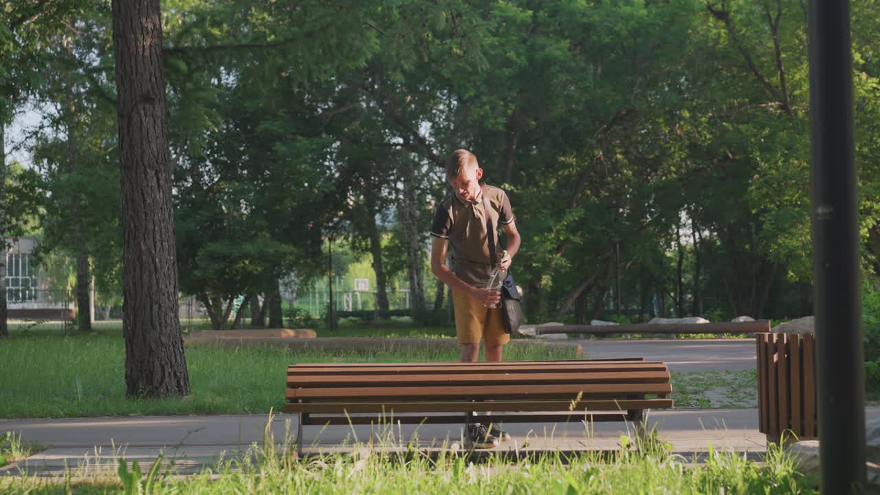 Man Examines Bench, Person Carefully Inspects Park Bench While Standing Under Bright Sunlight, Man In Casual Summer Clothing Examines Wooden Bench With Hesitation In Sunny Park Setting
