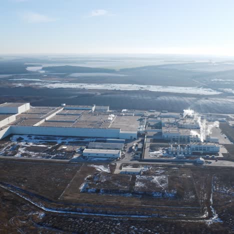 huge industrial plant among nature. view from the air on a modern factory surrounded by fields and forests in winter time. aerial view.