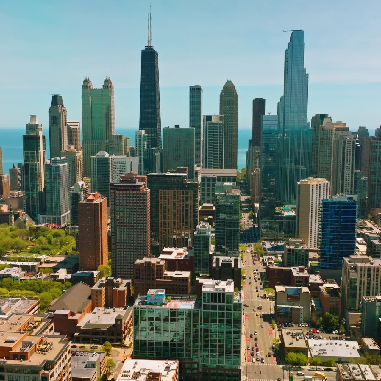 Long street of Chicago with busy traffic passing through skyscrapers. Amazing architecture at backdrop of blue sky