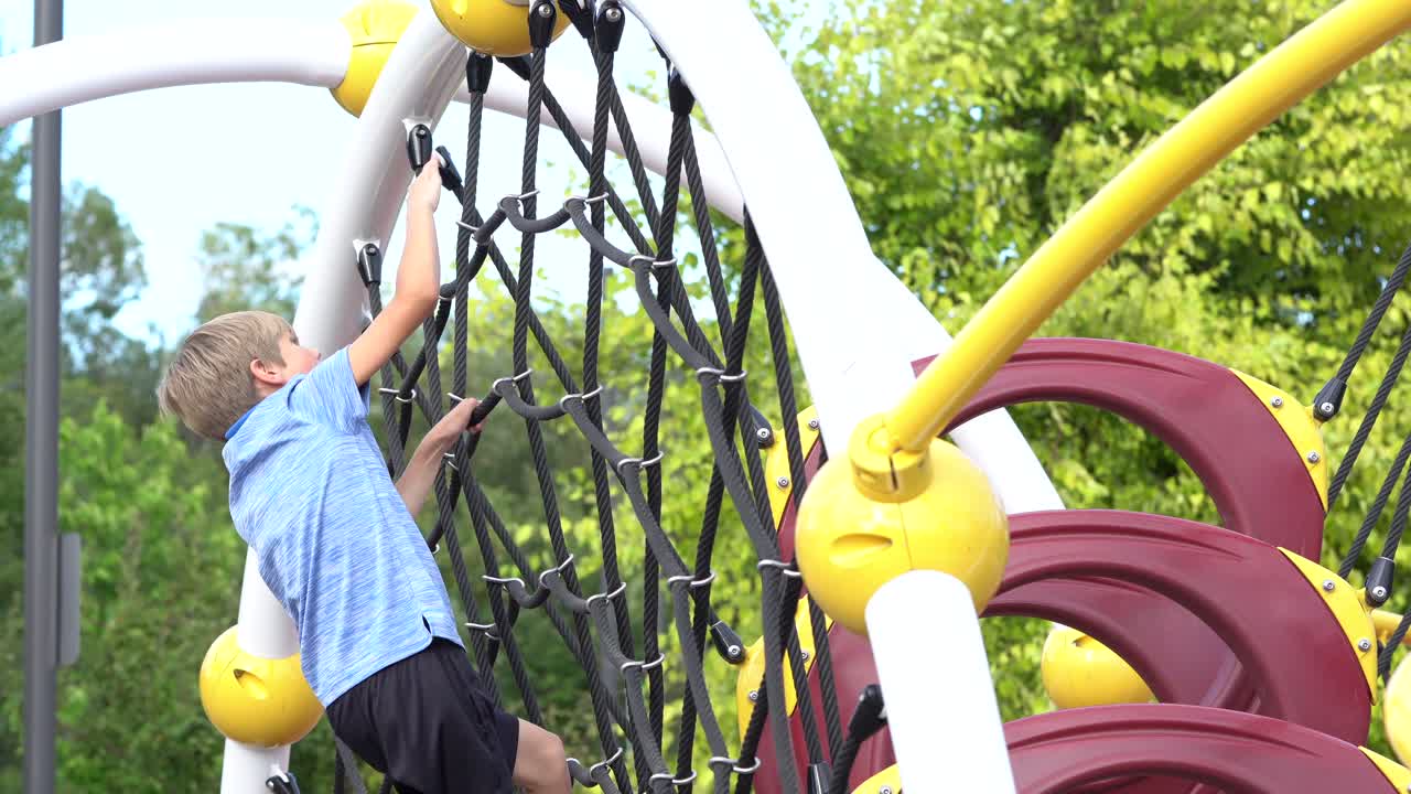 young white boy climbing playground equipment and back down