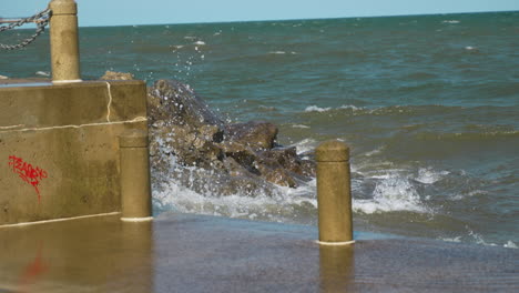 large wave crashes against seawall and flies up onto the ground in super slow motion