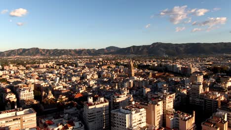 Drohnenaufnahme-Der-Stadt-Murcia-In-Spanien-Bei-Sonnenuntergang-Mit-Bergen-Im-Hintergrund