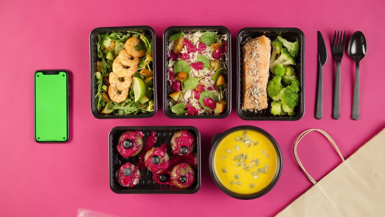 entrega de alimentos vista superior, llevar comidas en contenedores desechables en fondo rosa. cajas de almuerzo con platos vegetarianos cocidos, usando teléfono con pantalla verde croma. dieta saludable. servicio de catering