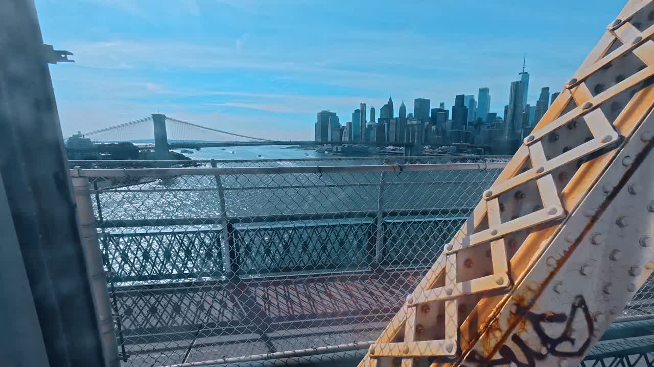 New York, USA, 5 maggio 2025: Skyline di Manhattan attraverso la recinzione e la struttura del ponte. Prospettiva grandangolare dello skyline di New York City visto attraverso recinzioni metalliche e travi d'acciaio arrugginite del Ponte di Manhattan