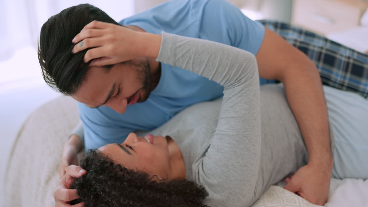 Amore, coppia giocosa e felice che si abbraccia sul letto