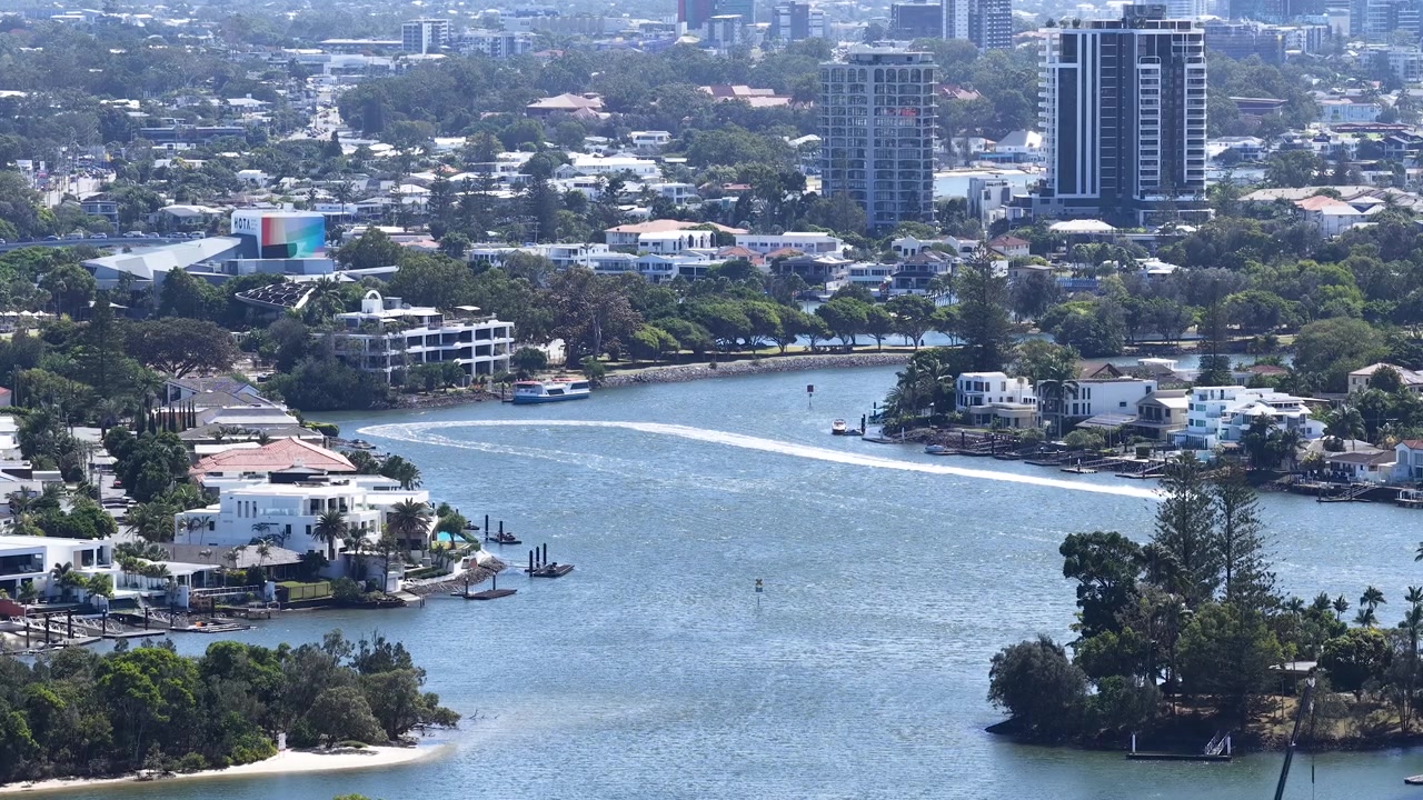 Plano aberto em ângulo alto de casas de luxo e arranha-céus ao longo da orla do Rio Nerang.